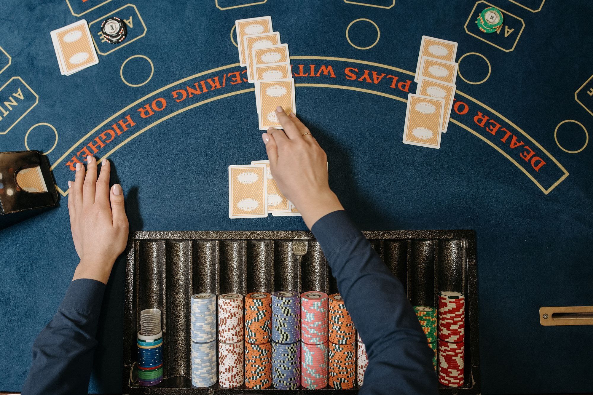 Croupier di blackjack che distribuisce le carte accanto al vassoio delle fiches, vista dall’alto